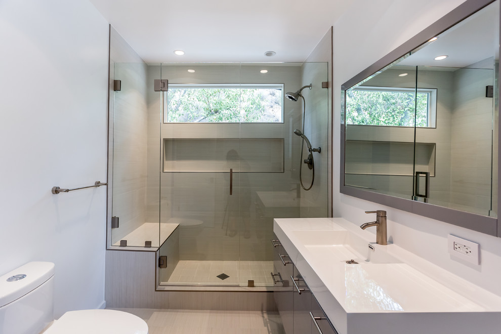 Modelo de cuarto de baño infantil minimalista grande con puertas de armario grises, ducha abierta, baldosas y/o azulejos beige, paredes blancas, lavabo integrado y encimera de cuarzo compacto