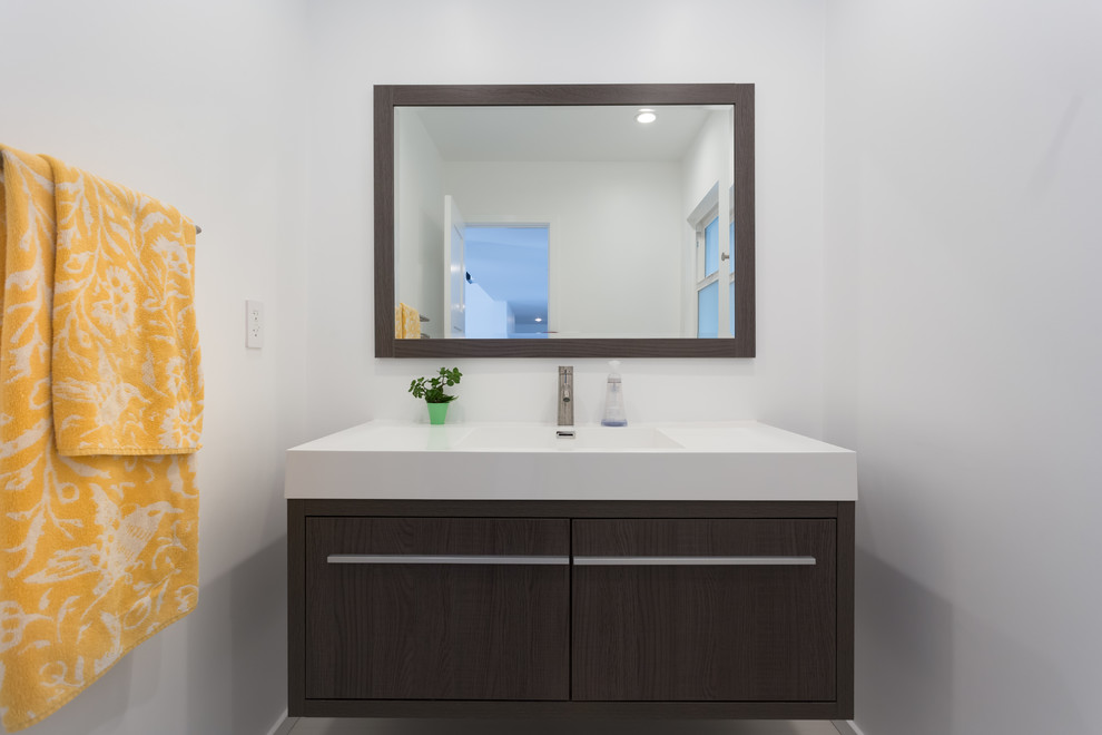 На фото: ванная комната среднего размера в стиле модернизм с темными деревянными фасадами, белой плиткой, белыми стенами, душевой кабиной, монолитной раковиной и столешницей из искусственного кварца с