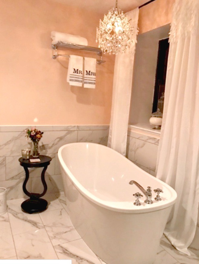 Photo of a small shabby-chic style ensuite bathroom in Other with open cabinets, a freestanding bath, a corner shower, white tiles, stone tiles, yellow walls, marble flooring, a pedestal sink, solid surface worktops, white floors and a hinged door.