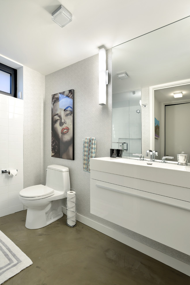 Modelo de cuarto de baño contemporáneo con armarios con paneles lisos, puertas de armario blancas, sanitario de una pieza, baldosas y/o azulejos blancos, suelo de cemento y encimera de cuarcita