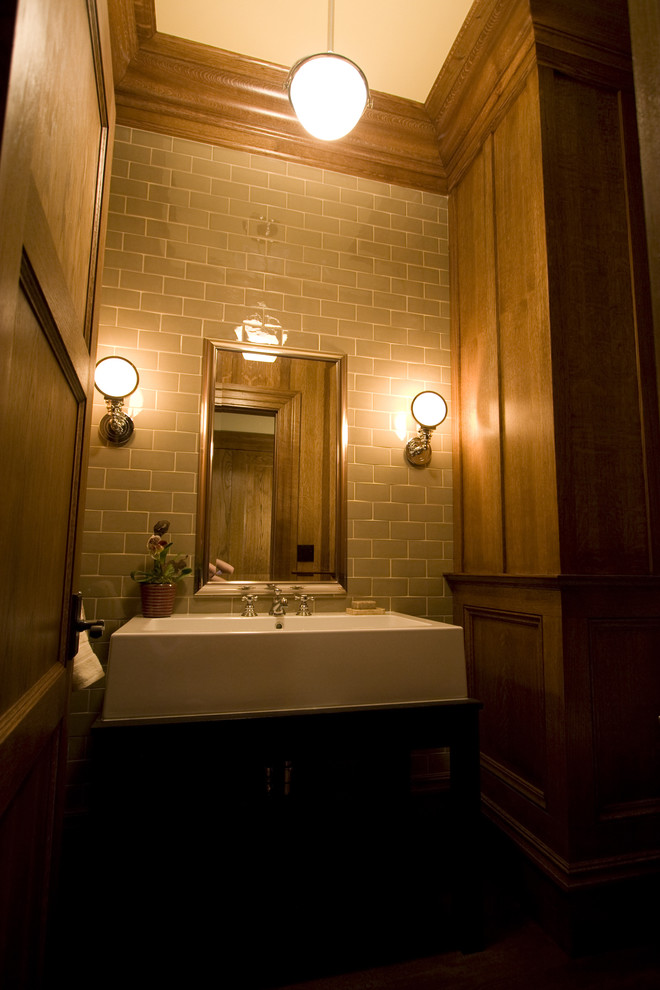 Cette image montre une salle de bain traditionnelle en bois foncé avec un placard à porte plane, un carrelage beige, mosaïque et un lavabo posé.