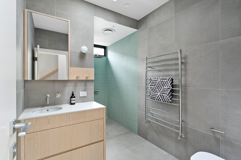 Immagine di una stanza da bagno padronale minimal con pareti grigie, ante lisce, ante in legno chiaro, doccia aperta, lavabo sottopiano, pavimento grigio e doccia aperta