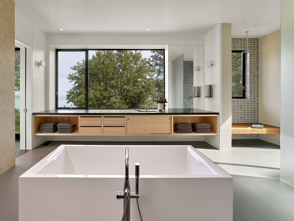 Idées déco pour une salle de bain principale contemporaine en bois clair de taille moyenne avec un placard à porte plane, une baignoire indépendante, une douche à l'italienne, un carrelage gris, un mur blanc, un lavabo encastré, un sol gris, aucune cabine, WC à poser, des carreaux de céramique, un sol en carrelage de porcelaine, un plan de toilette en quartz modifié et un plan de toilette marron.