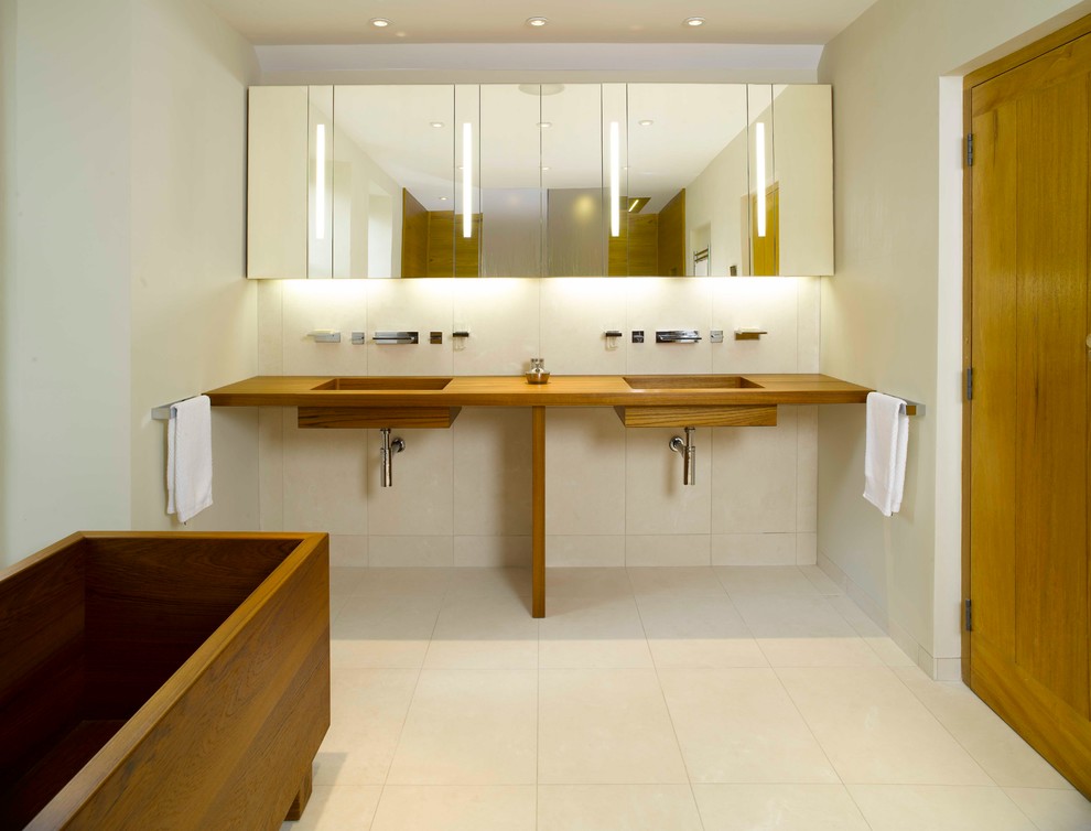 Réalisation d'une salle de bain minimaliste avec un lavabo intégré, un bain japonais, un carrelage beige et un mur blanc.