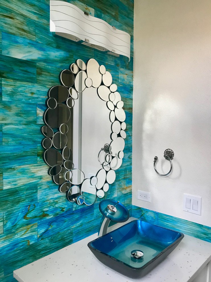 Modelo de cuarto de baño marinero pequeño con sanitario de una pieza, baldosas y/o azulejos azules, baldosas y/o azulejos de vidrio, paredes azules, aseo y ducha, lavabo con pedestal y encimera de cuarzo compacto