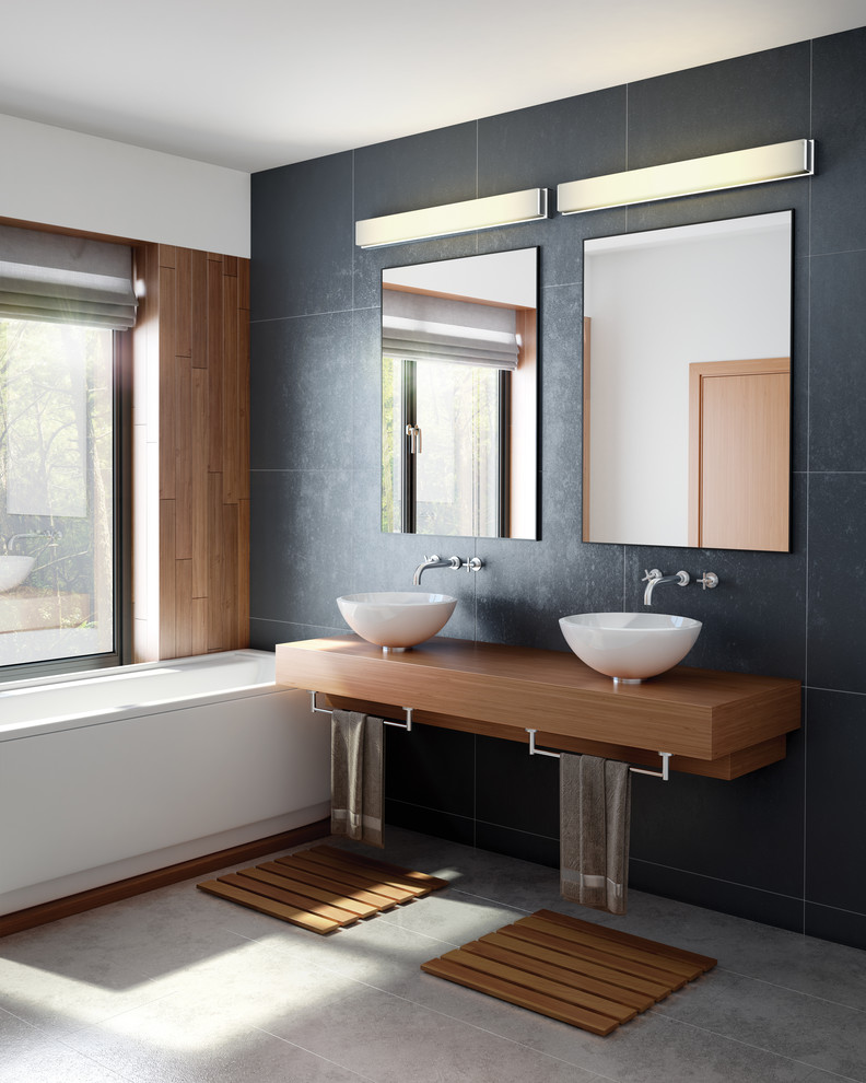 Design ideas for a medium sized contemporary ensuite bathroom in New York with black tiles, black walls, a pedestal sink, wooden worktops, open cabinets, medium wood cabinets, a built-in bath and grey floors.
