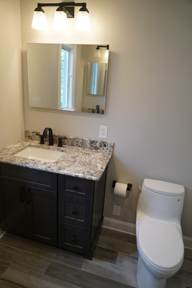 Inredning av ett modernt mellanstort grå grått badrum med dusch, med luckor med infälld panel, grå skåp, en dubbeldusch, en toalettstol med hel cisternkåpa, beige kakel, keramikplattor, grå väggar, klinkergolv i porslin, ett undermonterad handfat, granitbänkskiva, flerfärgat golv och dusch med gångjärnsdörr