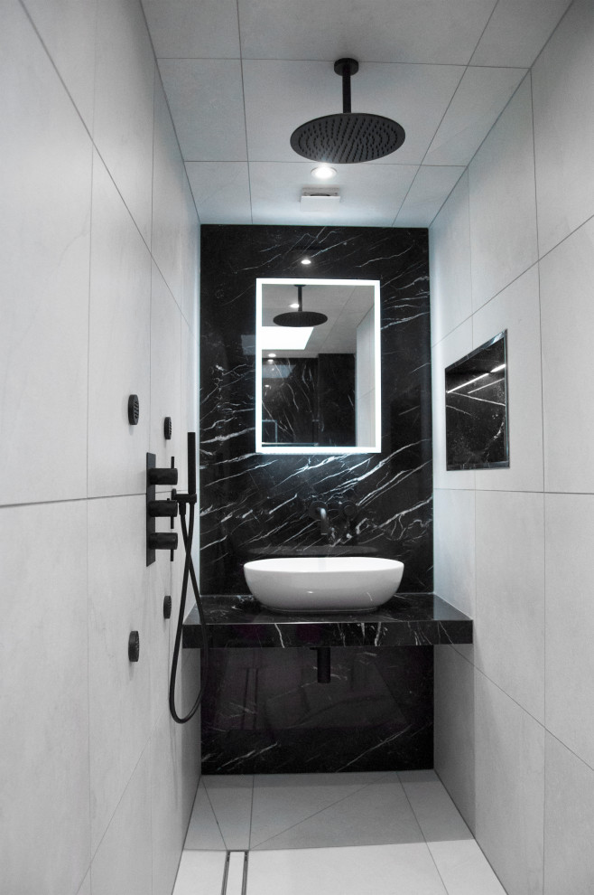 Bathroom - small modern 3/4 black and white tile and marble tile marble floor and white floor bathroom idea in London with flat-panel cabinets, black cabinets, a wall-mount toilet, white walls, a vessel sink, marble countertops and black countertops