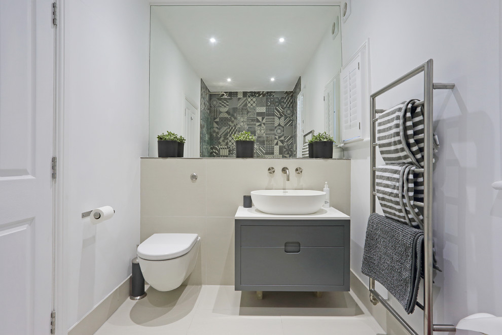This is an example of a medium sized contemporary grey and cream shower room bathroom in London with flat-panel cabinets, grey cabinets, a wall mounted toilet, white walls, a vessel sink, beige floors and white worktops.