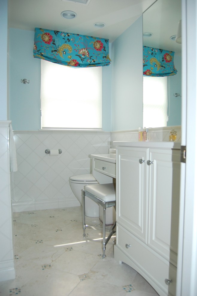 Exemple d'une salle de bain tendance de taille moyenne avec un placard avec porte à panneau surélevé, des portes de placard blanches, WC séparés, un carrelage blanc, des carreaux de céramique, un mur bleu, un sol en carrelage de céramique, un lavabo encastré, un plan de toilette en surface solide, un sol blanc et une cabine de douche à porte coulissante.