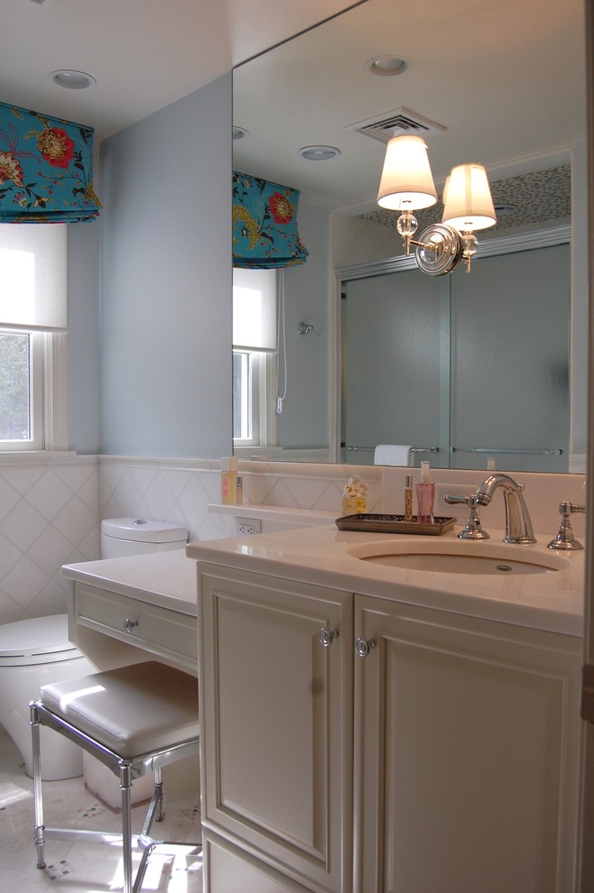 Cette photo montre une salle de bain tendance de taille moyenne avec un placard avec porte à panneau surélevé, des portes de placard blanches, WC séparés, un carrelage blanc, des carreaux de céramique, un mur bleu, un sol en carrelage de céramique, un lavabo encastré, un plan de toilette en surface solide, un sol blanc et une cabine de douche à porte coulissante.
