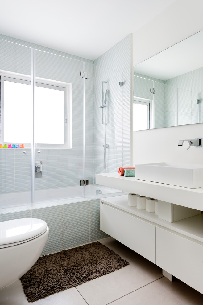 Modelo de cuarto de baño rectangular contemporáneo con lavabo sobreencimera, armarios con paneles lisos, puertas de armario blancas, bañera empotrada, combinación de ducha y bañera y baldosas y/o azulejos azules