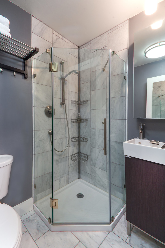 Bild på ett litet funkis badrum, med ett konsol handfat, släta luckor, skåp i mörkt trä, marmorbänkskiva, en hörndusch, en toalettstol med separat cisternkåpa, grå kakel, stenkakel, grå väggar och marmorgolv