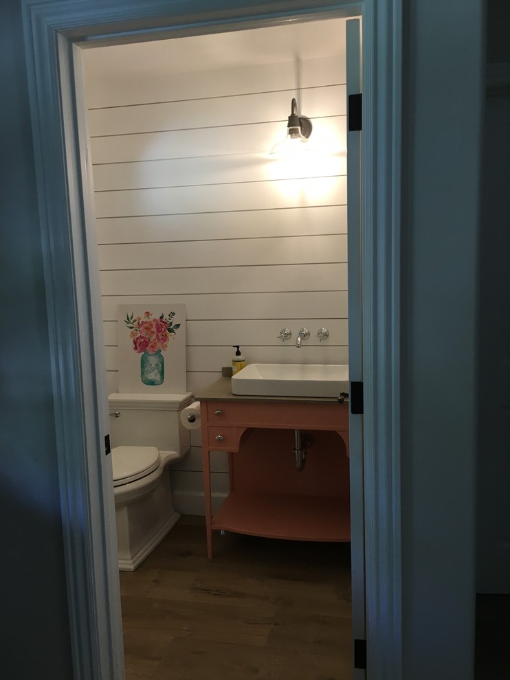 Cette photo montre une petite salle d'eau nature avec WC séparés, un placard en trompe-l'oeil, des portes de placard oranges, un mur blanc, un sol en bois brun, une vasque, un plan de toilette en bois et un sol marron.