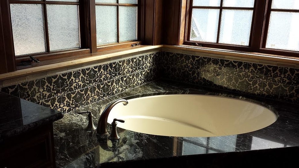Ispirazione per una stanza da bagno padronale tradizionale di medie dimensioni con vasca ad angolo, piastrelle di vetro, top in granito e pareti marroni