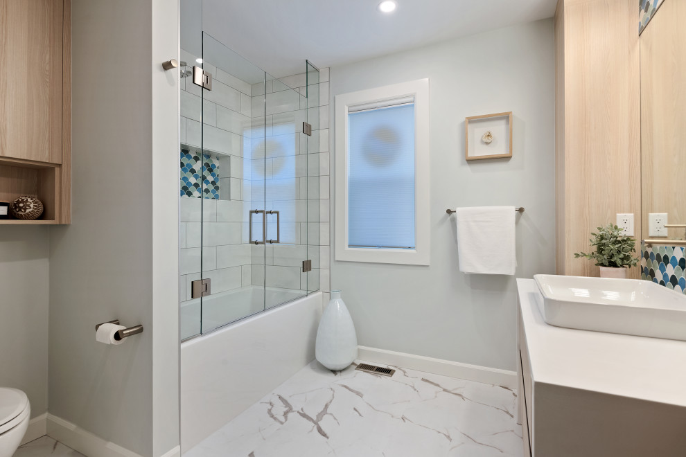 Bathroom - mid-sized modern master white tile and mosaic tile vinyl floor and multicolored floor bathroom idea in Calgary with flat-panel cabinets, light wood cabinets, a two-piece toilet, green walls, a vessel sink, quartz countertops, a hinged shower door and white countertops