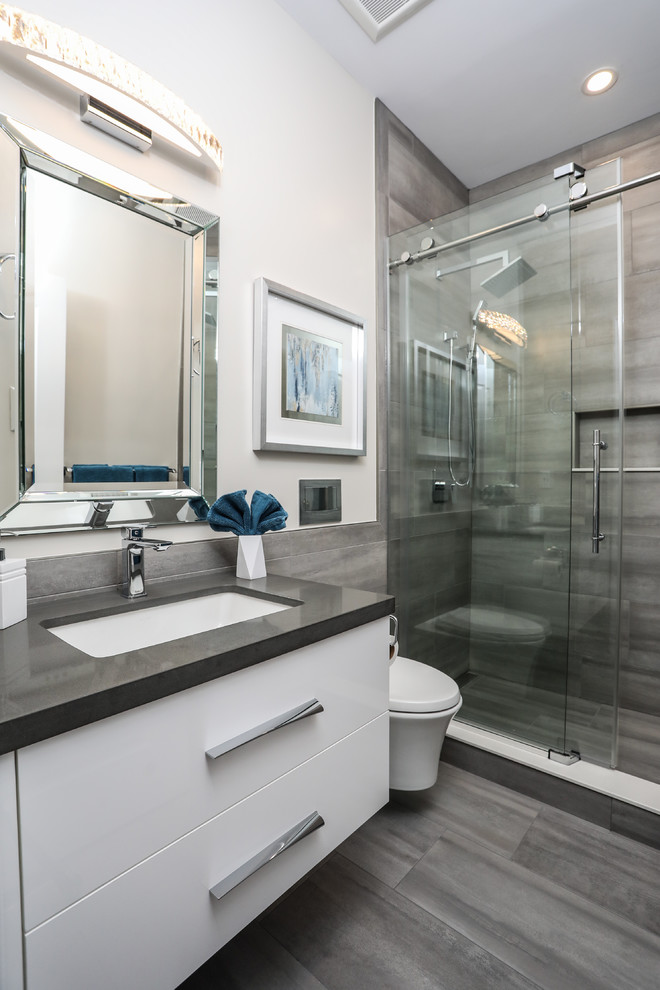 Bathroom - mid-sized modern master gray tile and porcelain tile porcelain tile and gray floor bathroom idea in Toronto with flat-panel cabinets, white cabinets, a wall-mount toilet, an undermount sink, quartz countertops and gray countertops