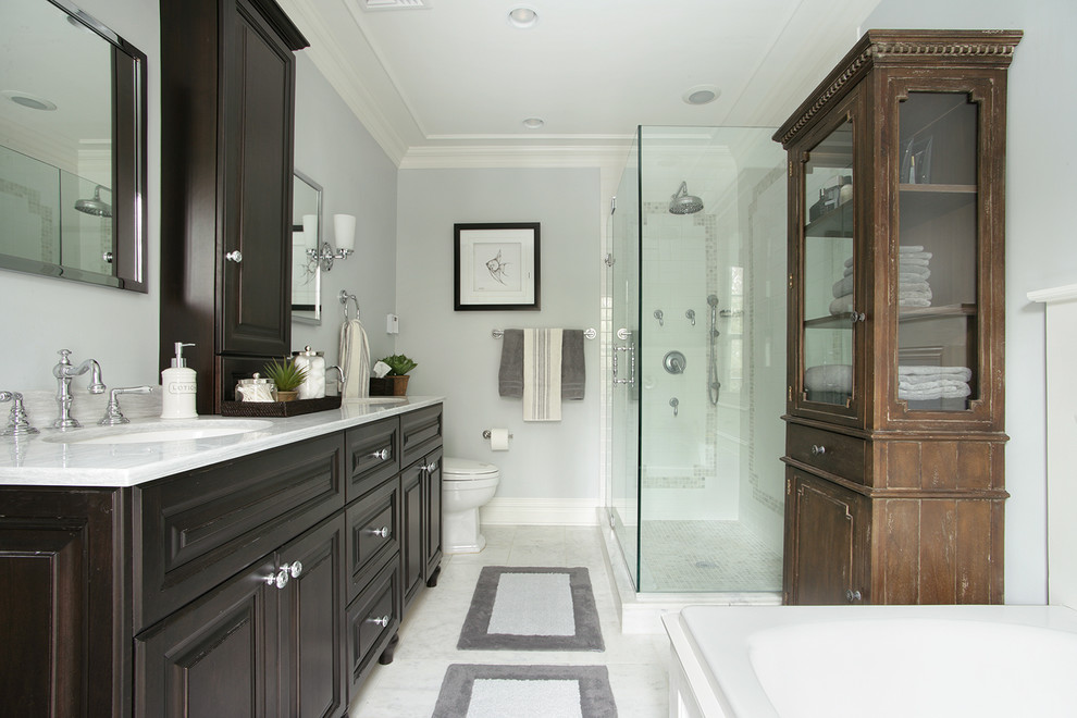 Inspiration pour une salle de bain traditionnelle en bois foncé avec un lavabo encastré, un placard avec porte à panneau surélevé, une baignoire posée, une douche d'angle et un mur gris.