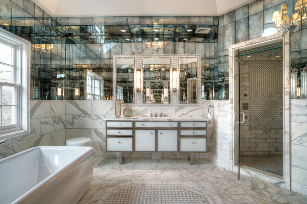 На фото: большая главная ванная комната в современном стиле с врезной раковиной, фасадами островного типа, белыми фасадами, мраморной столешницей, отдельно стоящей ванной, душем в нише, белой плиткой, зеркальной плиткой, белыми стенами и полом из мозаичной плитки с