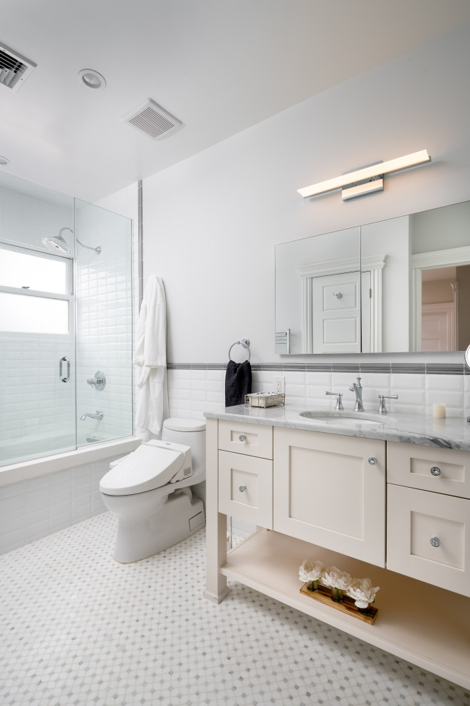 Aménagement d'une salle de bain classique avec un placard à porte shaker, des portes de placard blanches, une baignoire en alcôve, un combiné douche/baignoire, un carrelage blanc, un carrelage métro, un mur blanc, un sol en carrelage de terre cuite, un lavabo encastré, un sol blanc et un plan de toilette gris.