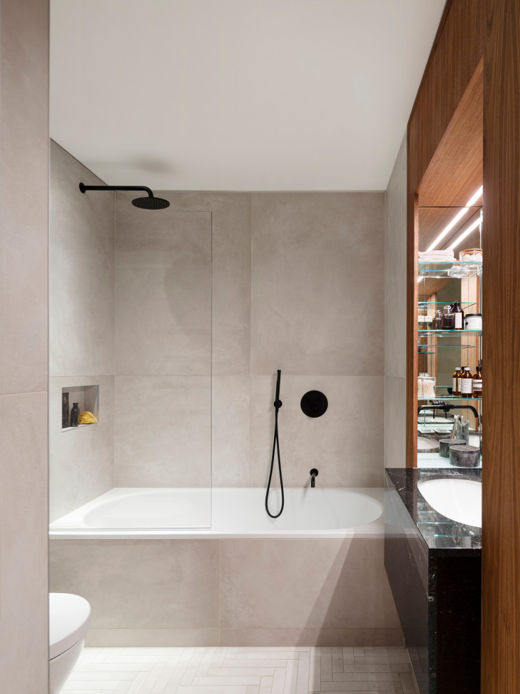 This is an example of a large contemporary bathroom in London with an alcove shower, a wall mounted toilet, grey tiles, ceramic tiles, grey walls, ceramic flooring, a submerged sink, granite worktops, a hinged door and black worktops.