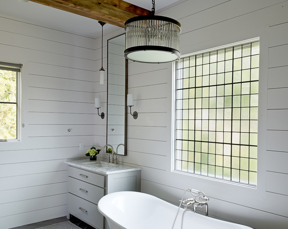 Example of a mid-sized transitional master porcelain tile and gray floor freestanding bathtub design in Other with blue walls, flat-panel cabinets, gray cabinets, marble countertops and an undermount sink
