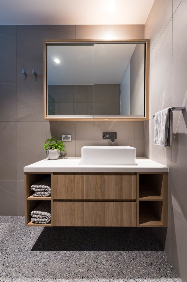 Стильный дизайн: главная ванная комната в современном стиле с светлыми деревянными фасадами, серой плиткой, серыми стенами, настольной раковиной, столешницей из искусственного кварца, белой столешницей и бетонным полом - последний тренд