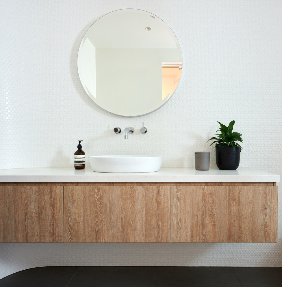 Cette photo montre une salle de bain principale tendance en bois brun de taille moyenne avec un placard sans porte, un carrelage blanc, une plaque de galets, un mur blanc, un sol en travertin, un plan vasque et un plan de toilette en granite.