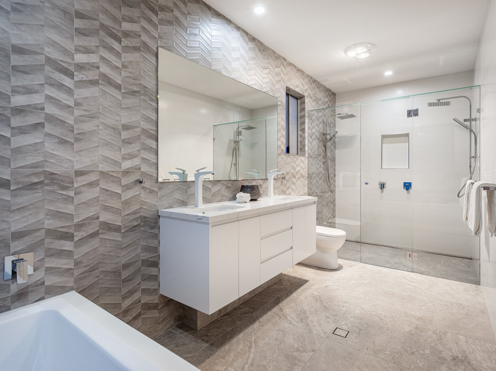 Inredning av ett modernt beige beige badrum med dusch, med släta luckor, vita skåp, ett badkar i en alkov, en dubbeldusch, grå kakel, ett undermonterad handfat, grått golv och dusch med gångjärnsdörr