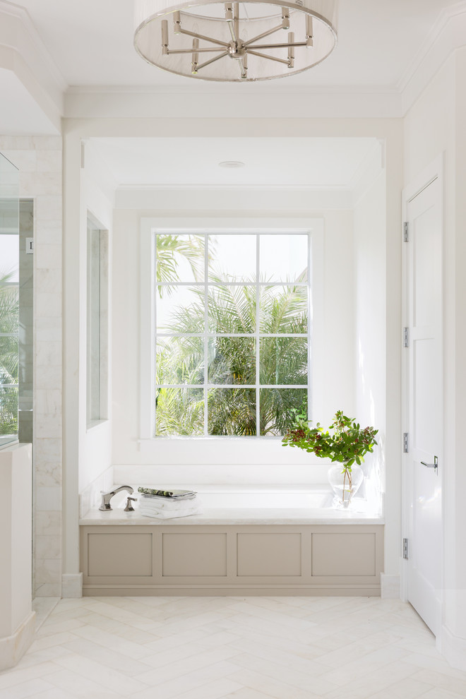 Exemple d'une grande salle de bain principale bord de mer avec un placard à porte shaker, des portes de placard beiges, une baignoire encastrée, une douche ouverte, un carrelage blanc, un carrelage de pierre, un mur blanc, un sol en marbre et un plan de toilette en marbre.