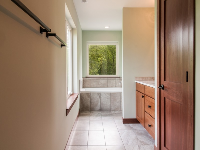 Aménagement d'une salle d'eau classique en bois brun de taille moyenne avec un placard à porte shaker, une baignoire posée, un carrelage beige, du carrelage en pierre calcaire, un mur blanc, un sol en calcaire, un lavabo encastré, un plan de toilette en granite et un sol beige.
