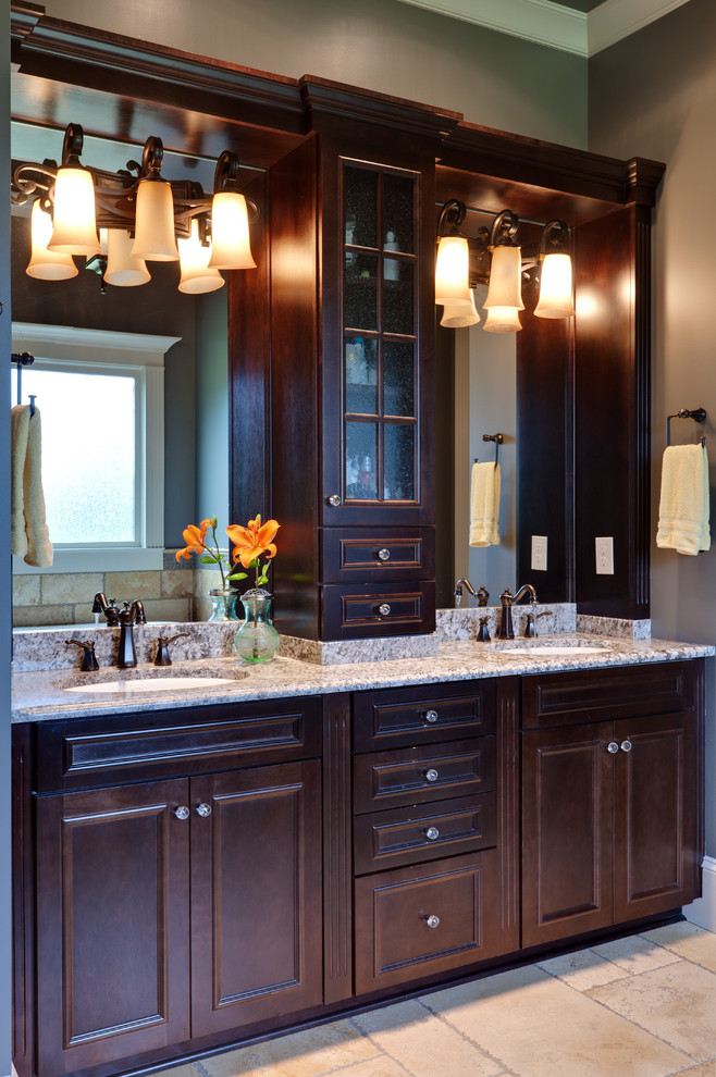 Ejemplo de cuarto de baño clásico con lavabo bajoencimera, armarios con paneles empotrados, puertas de armario de madera en tonos medios y baldosas y/o azulejos beige