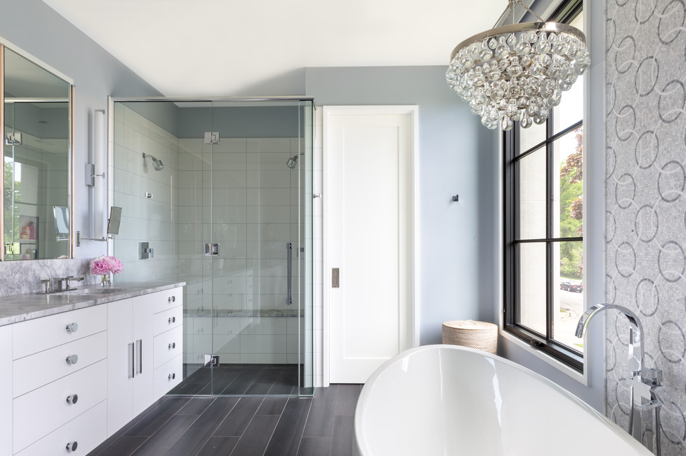 Exempel på ett mellanstort modernt grå grått en-suite badrum, med vita skåp, ett fristående badkar, en kantlös dusch, vit kakel, blå väggar, klinkergolv i porslin, ett undermonterad handfat, bänkskiva i onyx, grått golv, dusch med gångjärnsdörr, porslinskakel och släta luckor