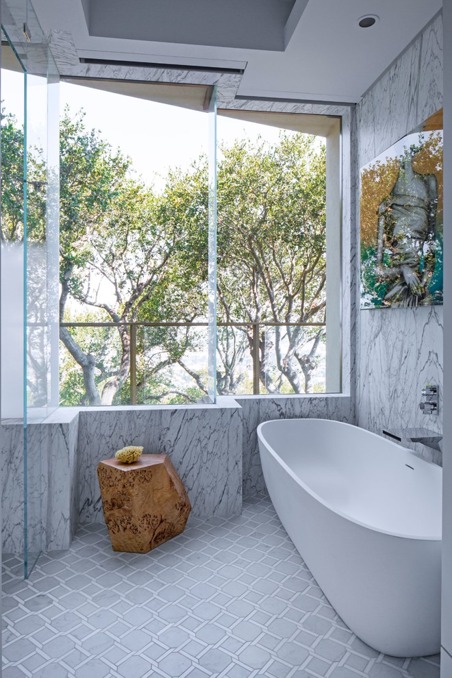 Inredning av ett modernt en-suite badrum, med ett fristående badkar, grå kakel, stenhäll, grå väggar och grått golv