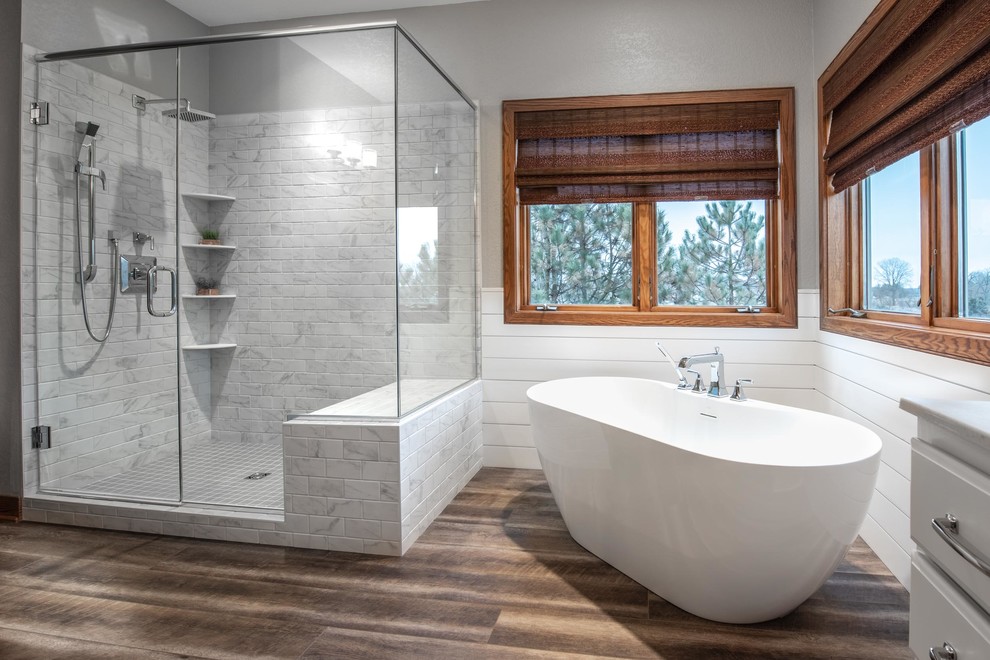 Idéer för att renovera ett mellanstort lantligt en-suite badrum, med luckor med upphöjd panel, grå skåp, ett fristående badkar, en hörndusch, grå kakel, keramikplattor, grå väggar, vinylgolv, ett integrerad handfat, bänkskiva i akrylsten, brunt golv och dusch med gångjärnsdörr