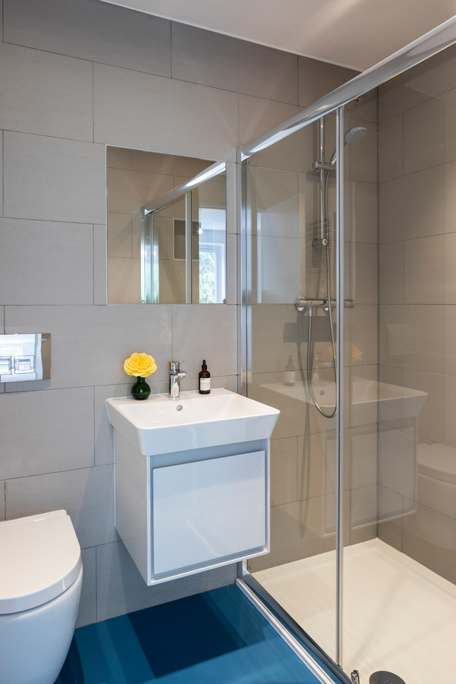 Inspiration for a contemporary gray tile blue floor alcove shower remodel in London with flat-panel cabinets, white cabinets, a wall-mount toilet, gray walls, a console sink and a hinged shower door