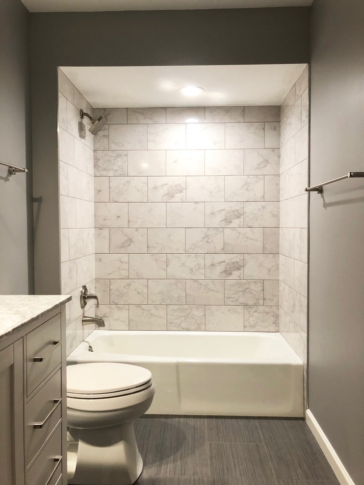 Example of a mid-sized trendy master white tile and ceramic tile porcelain tile and gray floor bathroom design in Columbus with furniture-like cabinets, brown cabinets, a two-piece toilet, gray walls, an undermount sink, quartz countertops and white countertops