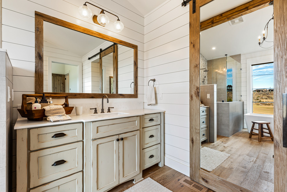 Inredning av ett lantligt mellanstort grå grått en-suite badrum, med möbel-liknande, grå skåp, en öppen dusch, vit kakel, cementkakel, vita väggar, mellanmörkt trägolv, ett undermonterad handfat, bänkskiva i kvarts, brunt golv och med dusch som är öppen