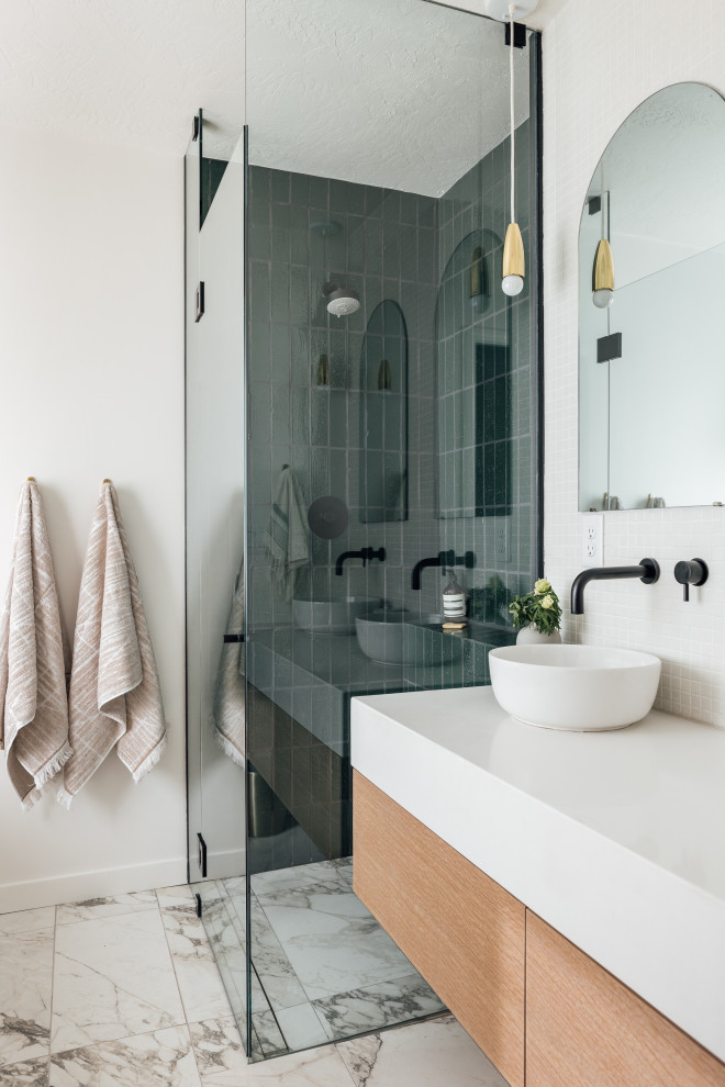 Exempel på ett mellanstort modernt en-suite badrum, med släta luckor, ett fristående badkar, en hörndusch, vit kakel, vita väggar, marmorgolv, dusch med gångjärnsdörr, skåp i ljust trä, mosaik, ett fristående handfat och vitt golv