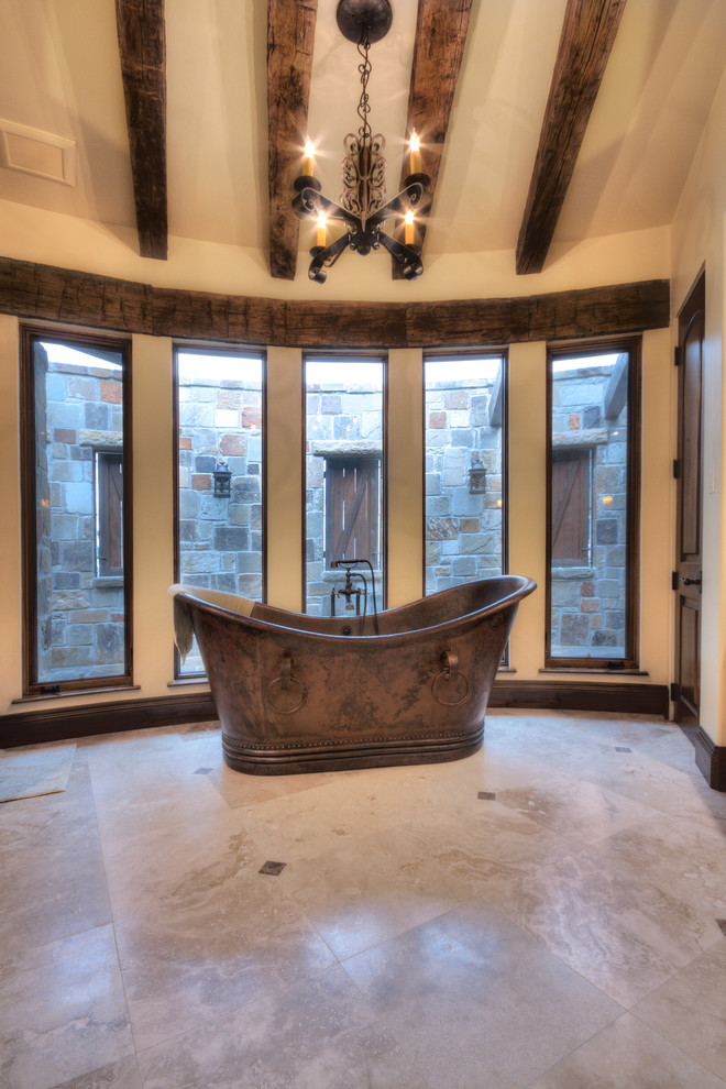 Imagen de cuarto de baño mediterráneo con bañera exenta, baldosas y/o azulejos beige y ventanas