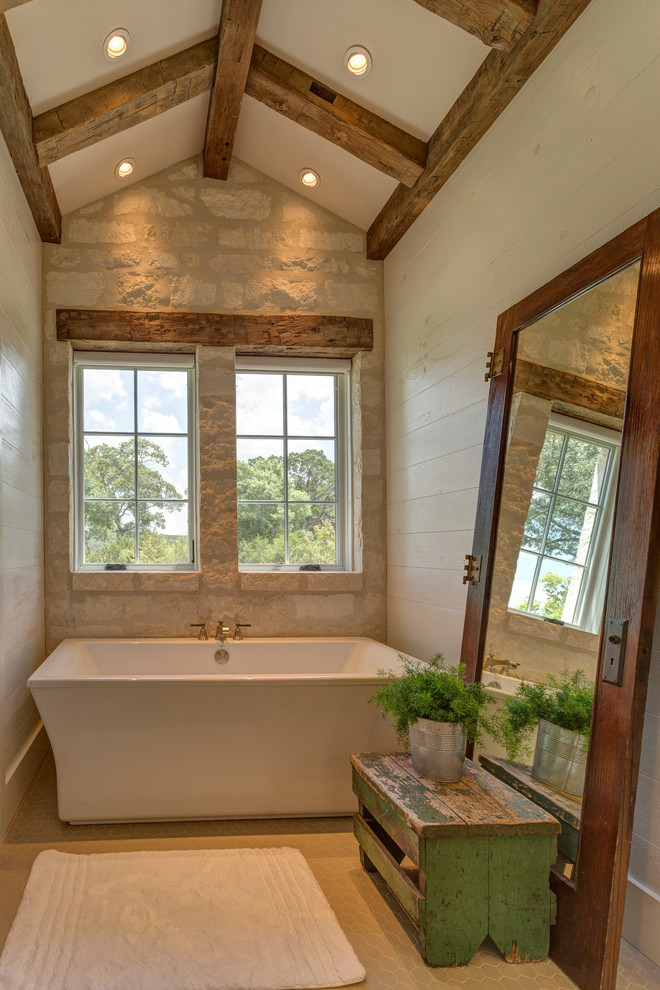 オースティンにあるカントリー風のおしゃれなマスターバスルーム (置き型浴槽、白い壁、コンクリートの床、ベージュの床) の写真