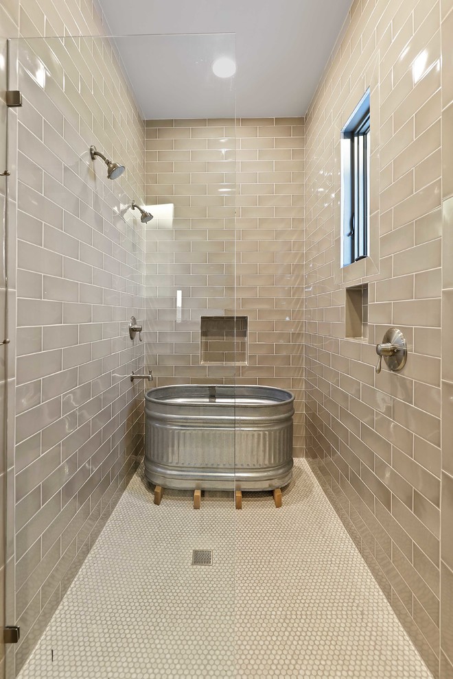 Cette image montre une très grande salle de bain principale chalet avec une baignoire indépendante, une cabine de douche à porte battante, une douche double, un carrelage beige, un carrelage métro, un sol beige et une fenêtre.