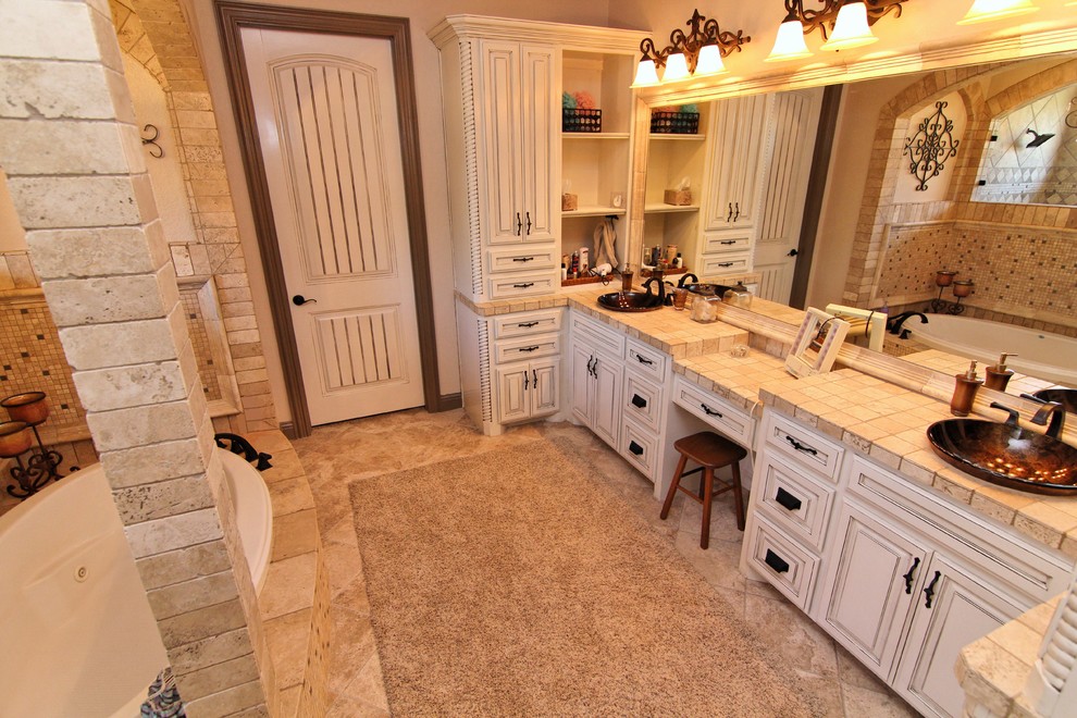 Photo of a medium sized traditional bathroom in Dallas with a vessel sink, raised-panel cabinets, distressed cabinets, tiled worktops, a hot tub, a walk-in shower, beige tiles, ceramic tiles, beige walls and porcelain flooring.