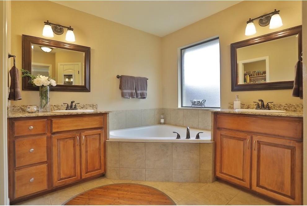This is an example of a medium sized classic ensuite bathroom in Atlanta with medium wood cabinets, granite worktops, a corner bath, beige tiles, ceramic tiles, beige walls, ceramic flooring and raised-panel cabinets.