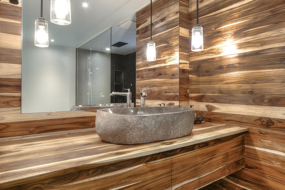 Bild på ett stort eklektiskt en-suite badrum, med släta luckor, skåp i ljust trä, en öppen dusch, en toalettstol med hel cisternkåpa, svart kakel, stenkakel, grå väggar, skiffergolv och träbänkskiva
