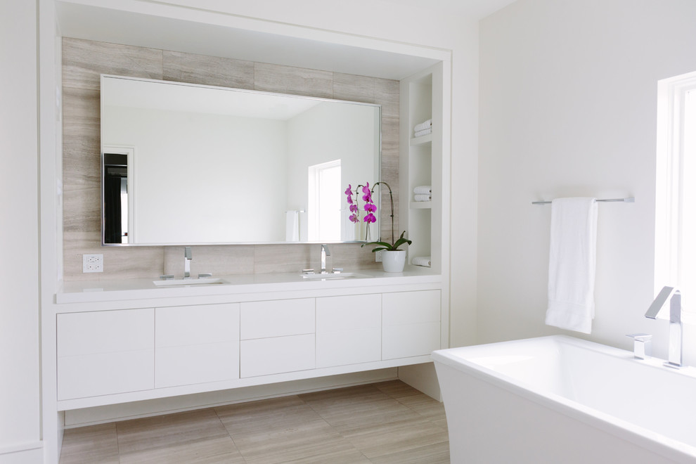 Photo of a medium sized modern bathroom in Chicago with beaded cabinets, a built-in sink, tiled worktops, multi-coloured floors, white cabinets, a freestanding bath, white walls, light hardwood flooring and white worktops.