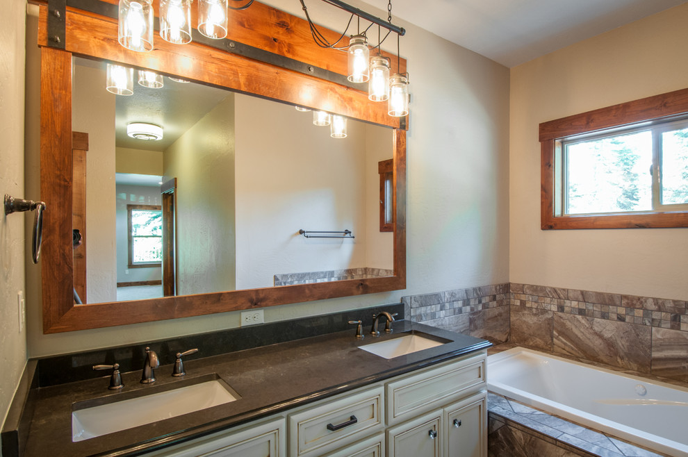 Esempio di una stanza da bagno padronale american style di medie dimensioni con lavabo sottopiano, ante con bugna sagomata, ante con finitura invecchiata, top in granito, vasca da incasso, piastrelle multicolore e pareti beige