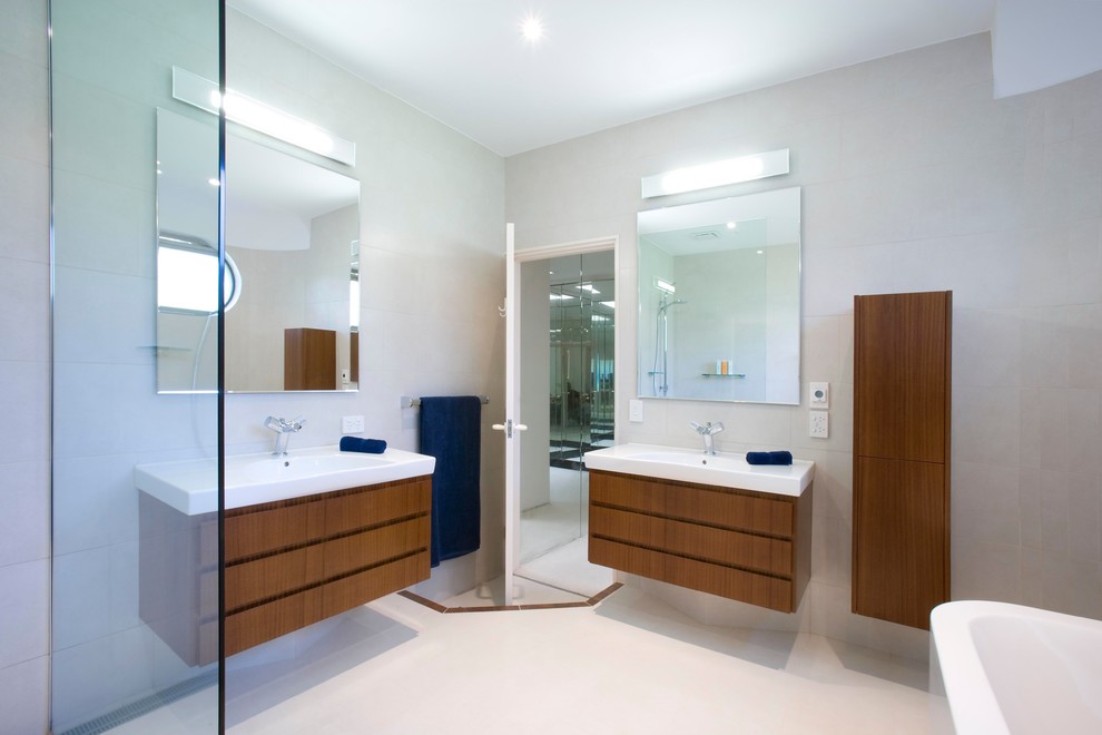 Cette photo montre une grande salle de bain principale tendance en bois brun avec un placard en trompe-l'oeil, un plan de toilette en surface solide, un carrelage blanc, des carreaux de porcelaine, un lavabo intégré, un mur blanc et un sol en carrelage de porcelaine.