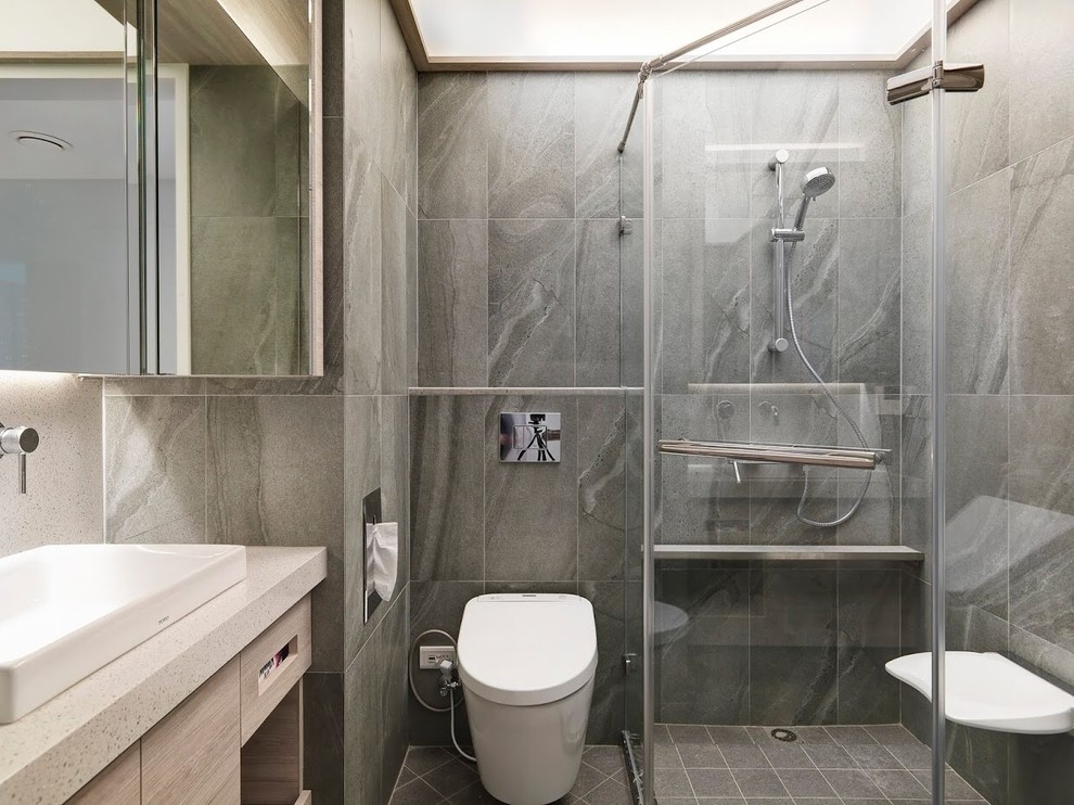 Bild på ett mellanstort funkis en-suite badrum, med vita skåp, våtrum, en vägghängd toalettstol, grå kakel, keramikplattor, grå väggar, klinkergolv i keramik, ett nedsänkt handfat, bänkskiva i kalksten, grått golv och dusch med gångjärnsdörr