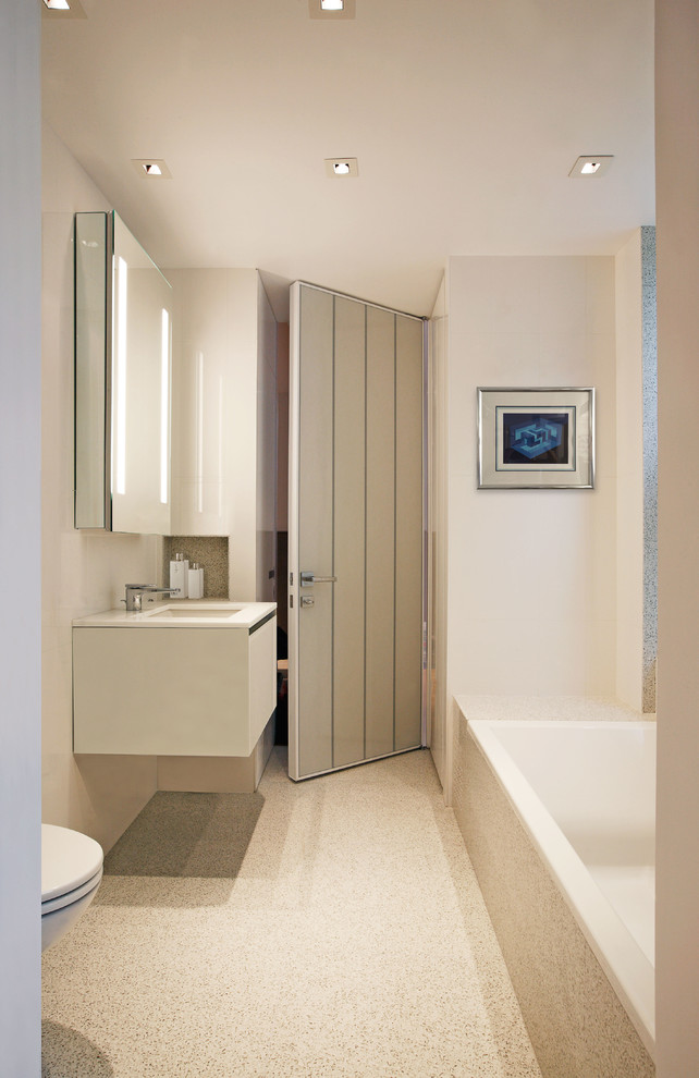 Inspiration för ett mellanstort funkis badrum, med släta luckor, vita skåp, ett badkar i en alkov, en dusch/badkar-kombination, en vägghängd toalettstol och vita väggar